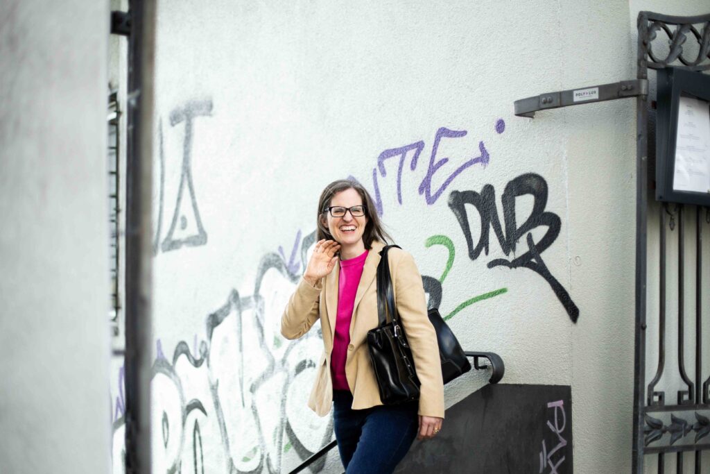 frau-harriet-beveridge-tisch-wand-graffiti-lachen-handtasche
