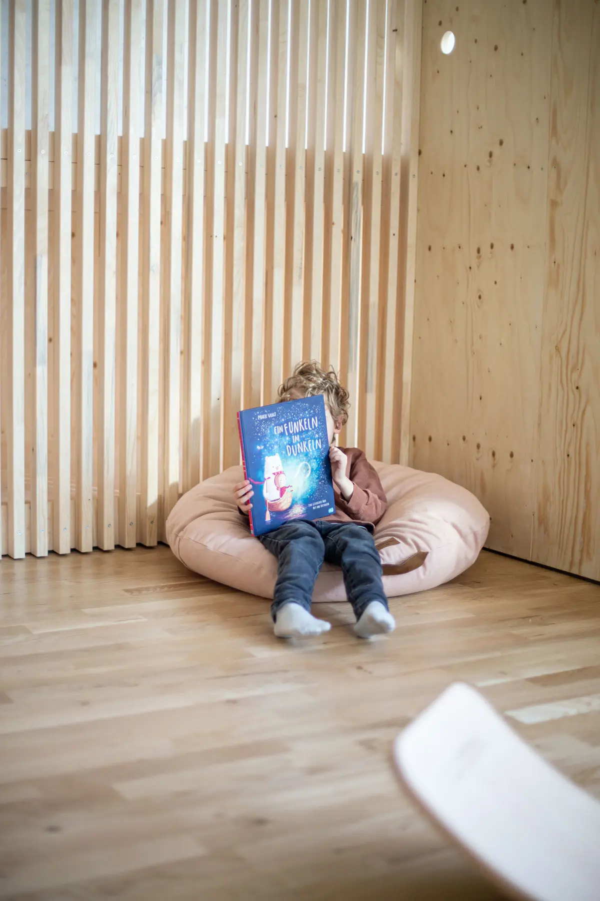 junge-kinderbuch-lesen-sitzsack-kissen-holzwand