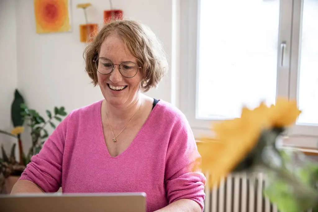 frau-pink-pullover-laptop-sonnenblume-fenster