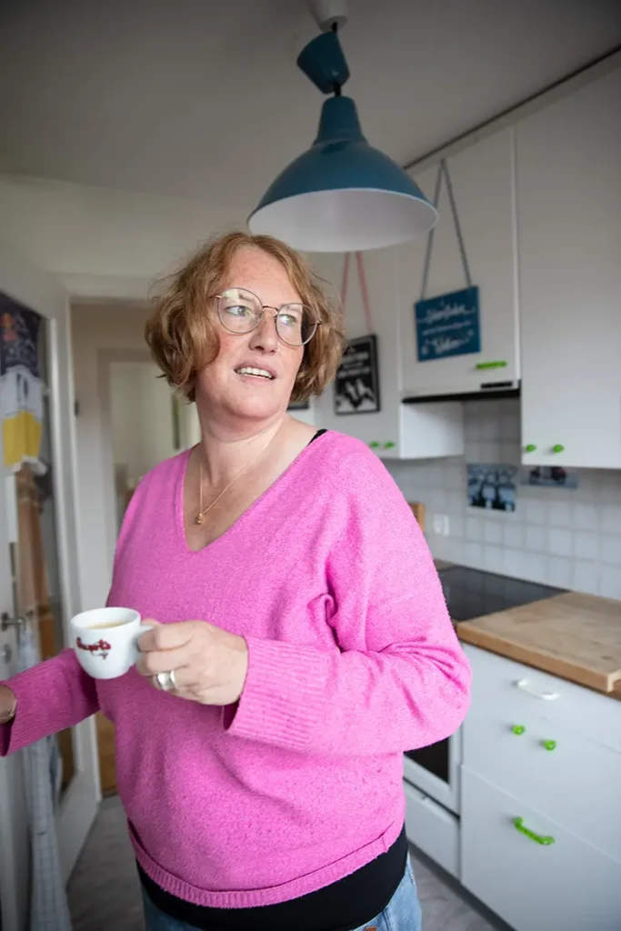 frau-küche-rote-haare-pink-pullover-tasse-tee-lampe-blau
