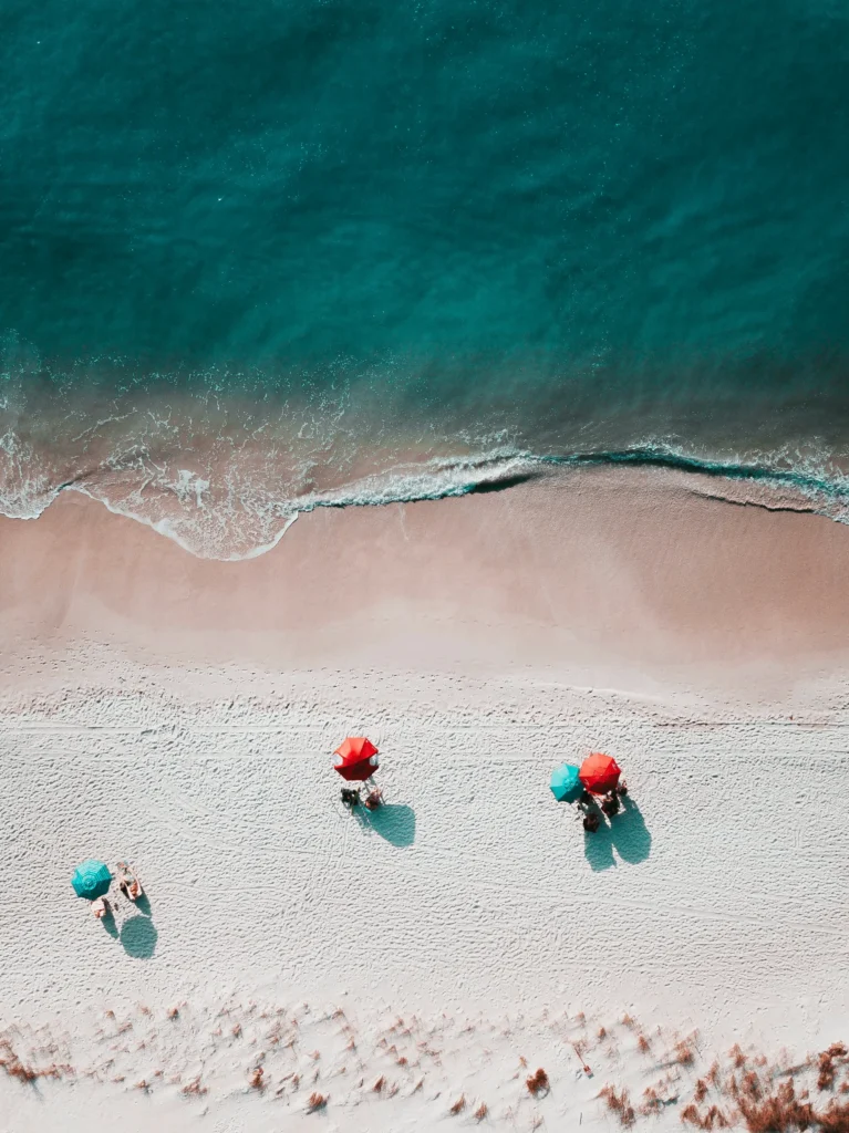 drohne-meer-sonnenschirme-rot-tuerkis-strand-sand
