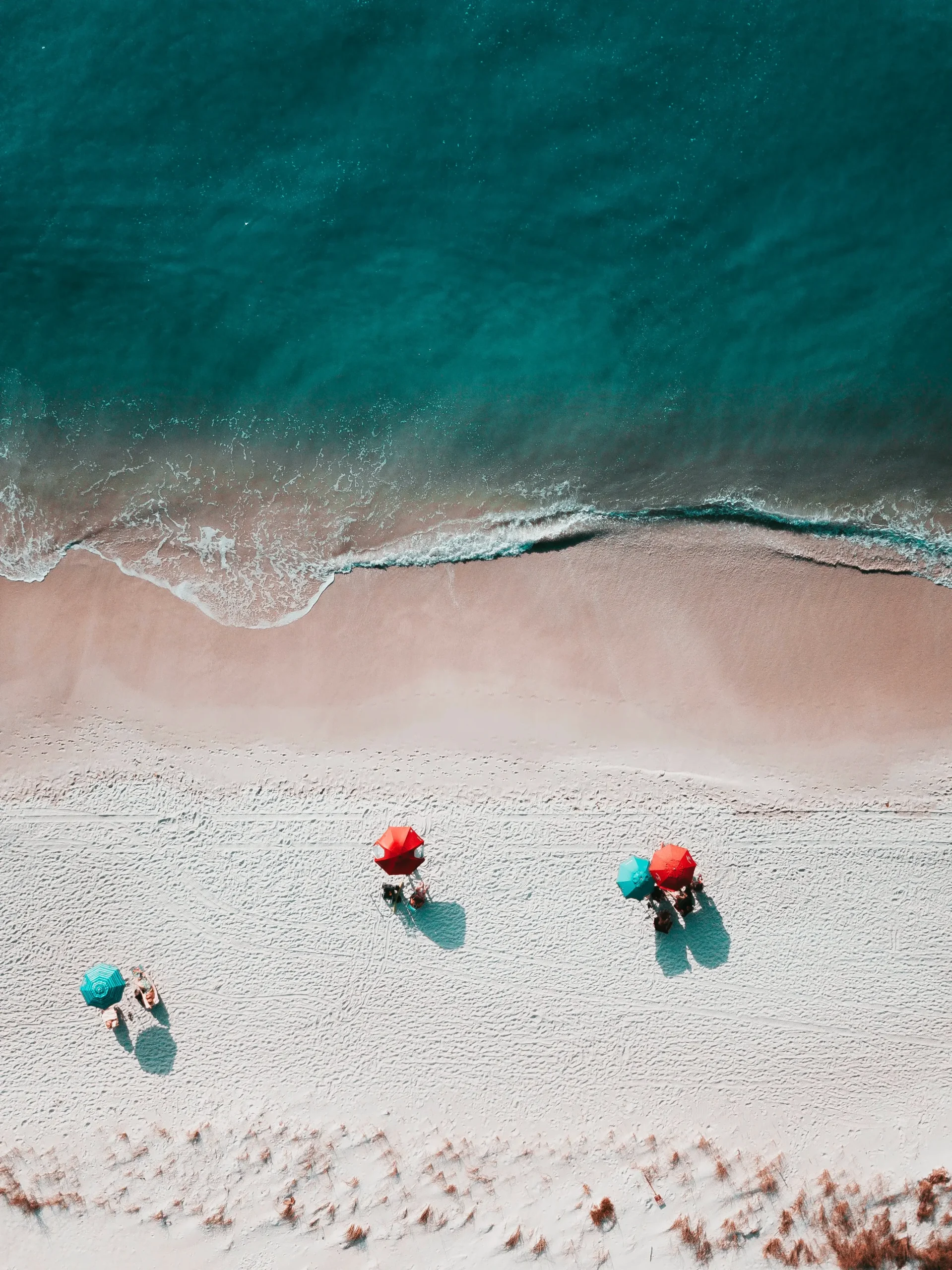 drohne-meer-sonnenschirme-rot-tuerkis-strand-sand