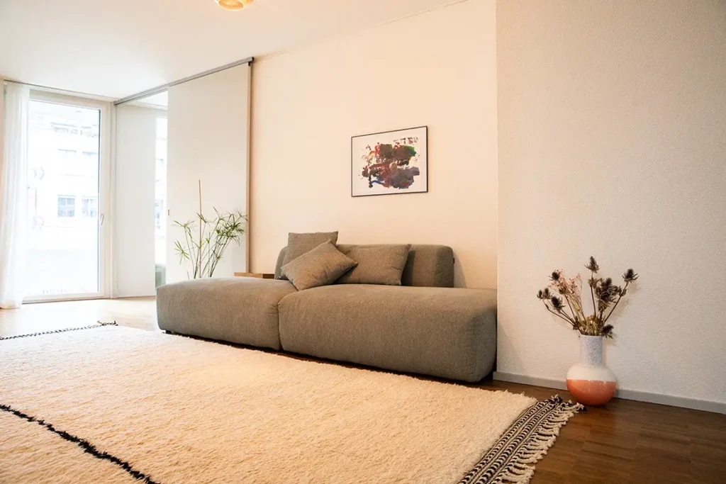 sofa-grau-teppich-weiss-vase-trockenblumen-bild-wand