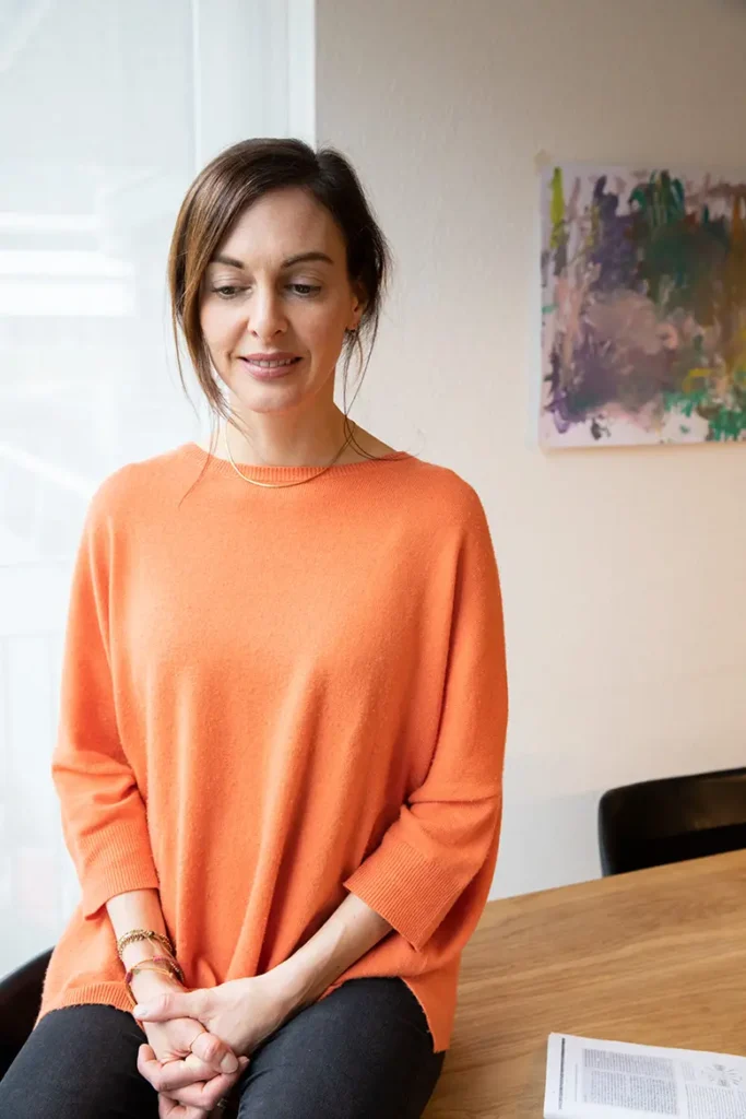 frau-porträt-orange-pullover-bild-hände-verschränkt