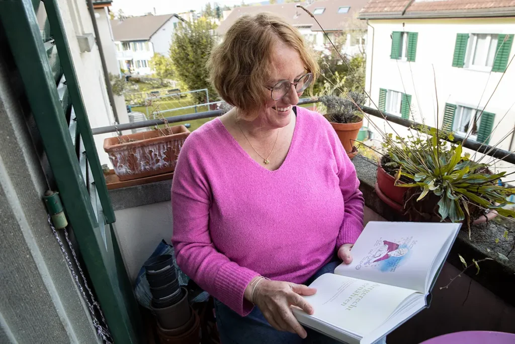 frau-balkon-pflanzen-kinderbuch-sitzen-fensterladen-pullover-pink