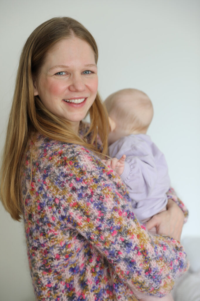 frau-rote-backen-baby-wolljacke-bunt