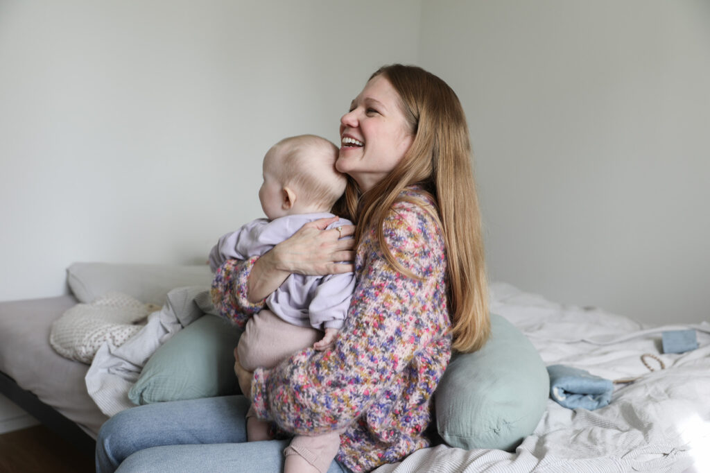 frau-baby-bett-stillkissen-wolljacke-bunt