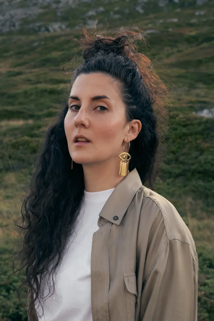 frau-locken-dunkle-haare-goldene-ohrringe-hemd-wiese