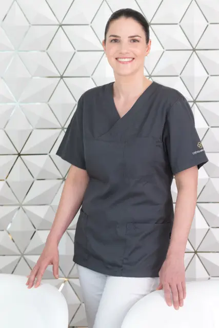 frau-ärztin-blaues-t-shirt-weisse-hose-wand-grau