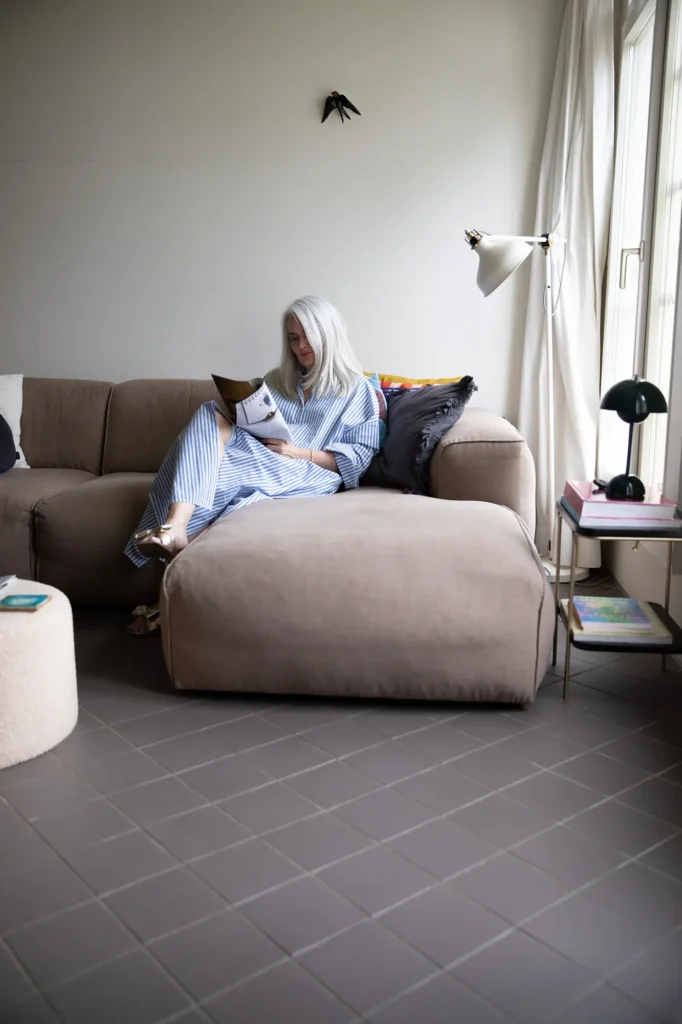 frau-gestreiftes-kleid-lesen-magazin-sofa-weisse-leuchte