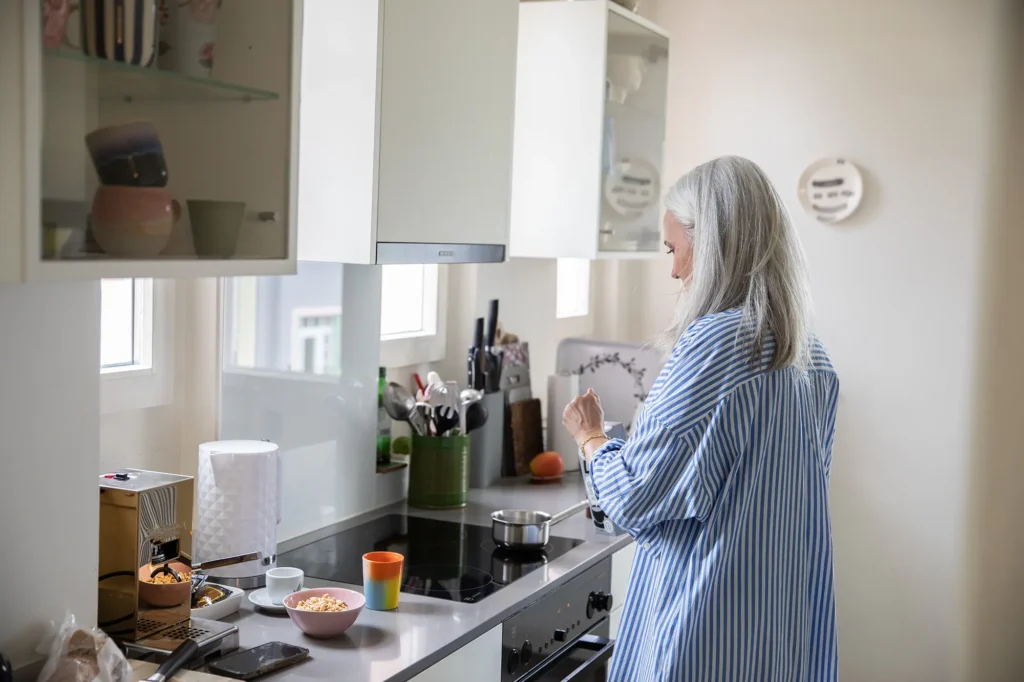 frau-gestreiftes-kleid-kueche-pflanzen-teetasse-weisse-haare