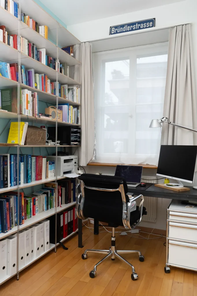 Büro-regalbuecher-weiss-stuhl-schwarz-buerolampe-computer