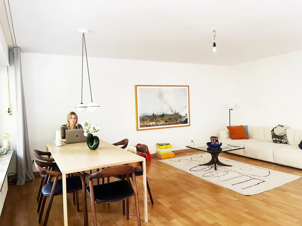 Motel-a-miio-keramik-anna-von-hellberg-tisch-holz-teppich-weiss-sofa-bild-stuehle-laptop-frau-arbeiten-vase