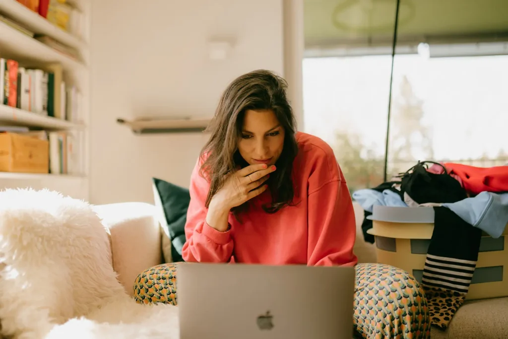 frau-oranger-pullover-laptop-arbeiten-wäschezaine-sofa