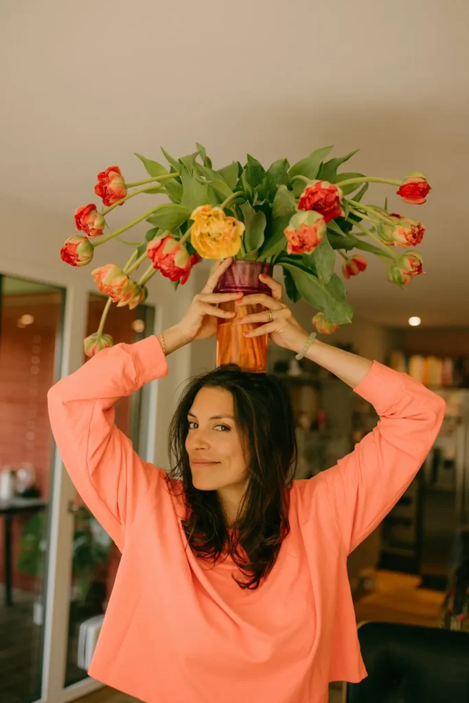 frau-oranger-pullover-dunkle-haare-rosen-blumenstrauss-verwelkt-vase-über-kopf