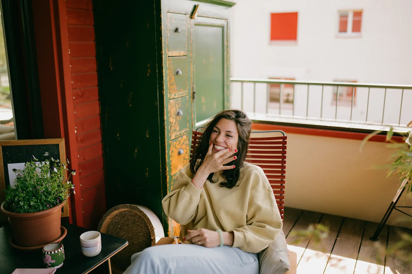 frau-pullover-terrasse-balkon-gewürz-roter-stuhl-lachen