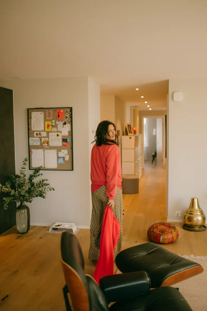 frau-wohnzimmer-pinwand-flur-dunkle-haare-oranger-pullover