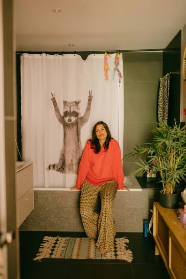 frau-oranger-pullover-bad-duschvorhang-waschbär-badewannenrand