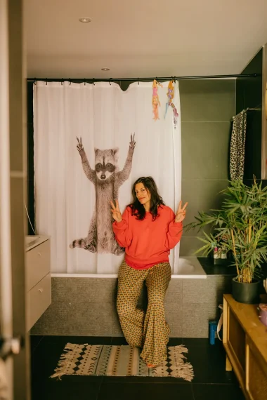 frau-oranger-pullover-bad-duschvorhang-waschbär-badewannenrand